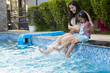 © GAJENDRRA BHATI  - Young indian mother and little child daughter enjoy splashing water at swimming pool in summer holiday, India Family having fun relaxing together at hotel resort vacation. Bonding and togetherness