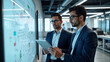 © redtiger9 - Two Indian engineers using tablet in front of whiteboard while discussing manufacturing process and product development in modern research facility
