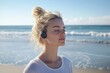 © YouraPechkin - Young woman enjoying music on a sunny beach while relaxing by the ocean waves
