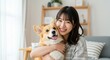 © AnilaStudio - 愛犬コーギーを抱きしめる笑顔の若い日本人女性 - 室内でのペットとの愛情あふれる瞬間、家族、癒やし、ペット関連広告、SNSコンテンツに