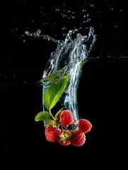 Fototapete - A clear glass vase filled with water and ice cubes, containing ripe red raspberries and green mint leaves.