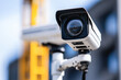 © Kiangdeb - Close-up of a modern security camera mounted outdoors with a blurred urban background