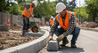 © abu - Road Construction Workers Laying Concrete Blocks For Road Edge in Bright Sunlight Wearing Hard Hats and Safety Vests