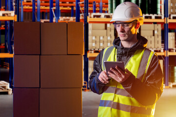 Poster - Man logistics warehouse worker. Fulfillment center employee. Logistics manager with e-tablet. Storekeeper in yellow vest in warehouse hangar. Man logistics center worker holding gadget.