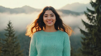 Poster - A woman in a green sweater stands at the base of a mountain, looking up towards the peak.