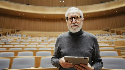 Poster - A lecturer holds a tablet during a class in a university lecture hall.