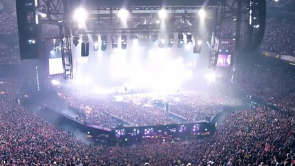 Poster - This Thousands gather under lights for an electrifying concert atmosphere in a packed arena.