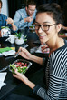 © peopleimages.com - Discussion, happy and portrait of woman with salad in office for team building lunch for collaboration. Meeting, smile and business with female designer with colleagues eating healthy in workplace