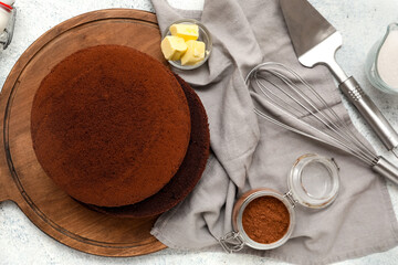 Wall Mural - wooden board with sponge cake layers, cocoa powder, butter, utensils and napkin on light background