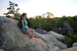 © bilanol - Sportive female hiker sitting alone taking a break on hillside trail. Lonely woman enjoying view of evening nature from rocky cliff on wilderness path. Active lifestyle concept