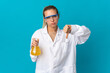 © luismolinero - Young scientific woman isolated on blue background showing thumb down with negative expression