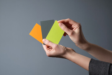 Aufkleber - Hands hold three color swatches: orange, gray, and lime green against a gray background Free space for text or logo Mockup for design presentation