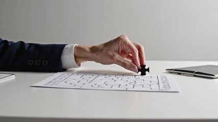 Aufkleber - Businessman in a suit places the last piece of a puzzle, solving a maze printed on a sheet of paper lying on a white table next to a laptop