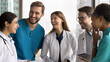 © fizkes - Team building moment. Happy friendly diverse multiethnic millennial doctors standing in circle at hospital workplace discuss funny patient case hold joyful conversation laughing collaborating as group