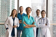 © fizkes - Contemporary standards in healthcare. Young modern day doctors international hospital medical workers pose for portrait together with young lady surgeon team leader in clinic office with window walls
