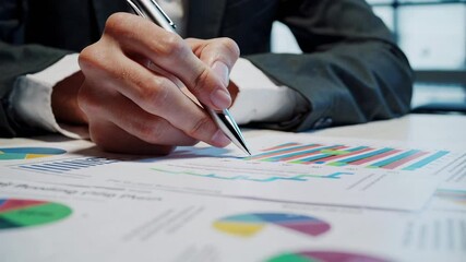 Poster - Businessman reviewing financial data, using a pen to point at charts and graphs, indicating a process of careful examination and strategic decision making in a corporate setting