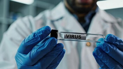 Poster - Medical scientist wearing a lab coat and protective blue gloves holding a transparent test tube containing a virus sample inside a laboratory