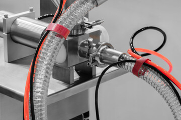 Aufkleber - A machine with a red and black hose attached to it. The hose is connected to a silver pipe