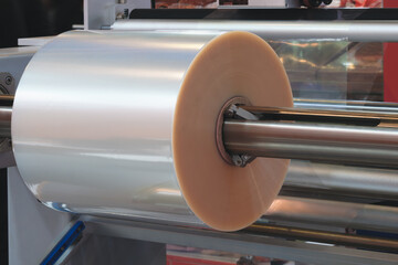 Poster - Automatic polyethylene plastic bag production machine with lighting effect. Close-up of the roller of the plastic bag production machine in the light blue scene. product packaging concept.