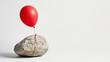 © koranis - Balloon tied to a heavy rock symbolizing hope held back by burden