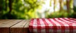 © ma - Rustic outdoor table setting: checkered red-white linen draped over weathered wood, shallow focus revealing blurred summer garden foliage and golden hour sunlight.