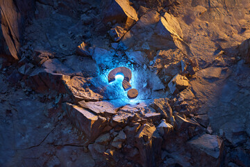 Poster - Glowing blue question mark embedded in rough, dark rocks, illuminated against a contrasting orange backdrop, suggesting mystery and enigma, ideal for inquisitive concepts