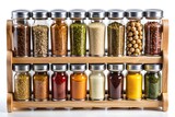 Close up of a wooden spice rack filled with glass jars containing various colorful spices and herbs
