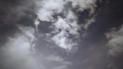 Wall Mural - Time lapse of moon-lit clouds moving across a sky with scattered clouds
