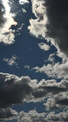 Wall Mural - Time lapse of backlit summer clouds with high contrast drifting through a blue sky
