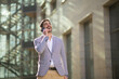 © Dexon Dee - Happy businessman talking on the phone outside a modern office building. Confident male professional having a pleasant conversation in a business environment.