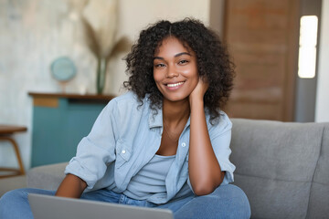 Aufkleber - Young woman working from home sitting on sofa using laptop smiling