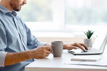 Poster - Remote Work. Handsome Male Freelancer Using Laptop And Drinking Coffee, Working Remotely At Home Office, Sitting At Desk Near Window, Browsing Internet, Having Online Job, Side View With Copy Space