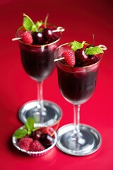 Aufkleber - Two glasses filled with red cocktails topped with raspberries and mint leaves on a red surface.