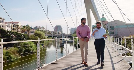 Poster - Tablet, discussion and business men on bridge in city with company budget planning in collaboration. Walking, digital technology and male financial managers with dividend account in urban town.