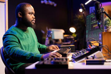 Leinwandbilder - Skilled music producer creating new songs on midi controller synthesizer, working with mixing console and professional software on pc. Male artist using piano and mastering acoustical tunes.