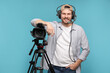 © New Africa - Man with professional video camera and headset on light blue background