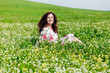 © dmitriisimakov - woman sitting in a field with flowers in spring and smiling