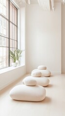 Poster - Calm and serene wellness space showcasing soft, rounded pillows arranged near a large window, allowing natural light to illuminate the tranquil environment