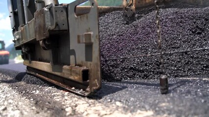 Fototapete - Asphalt paver screed during asphalt paving process, paving a new layer of asphalt at road construction site, close-up, low angle