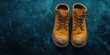 © Vergiliy - Worn yellow work boots on textured blue background showcasing rugged footwear style