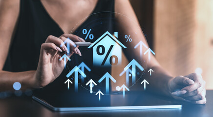 Poster - Digital mortgage interest rate growth concept with holographic house and arrows rising above tablet held by woman on blurred creative background.