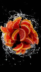 Aufkleber - Super slow motion of rotating Grapefruit slices with splash water, black background. Filmed on high speed cinema camera, 1000 fps. Vertical aspect ratio.