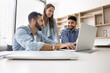 © fizkes - Productive teamwork. Mature businesswoman and two younger male colleagues of different ethnicities collaborate to solve problem using notebook discuss project on screen analyze data in corporate app