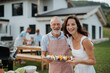 © Halfpoint - Older father and adult daughter preparing food for a family barbecue.