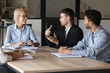 © fizkes - Young business professional man speaking at board meeting, executive people talk in a boardroom. Male leader project manager discussing report with diverse partner team. Office management work