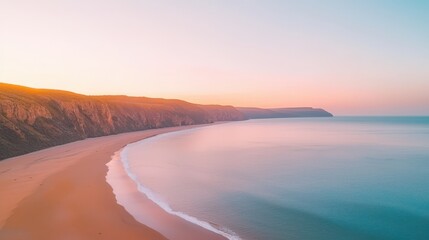 Wall Mural - Stunning aerial view of a serene coastline at sunset, showcasing gentle waves lapping against the sandy beach, surrounded by lush cliffs under a colorful sky.