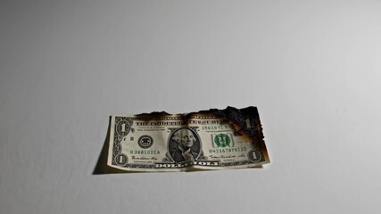 Aufkleber - Slow burning process of single dollar bill on pristine white background, symbolizing economic challenges, monetary devaluation, financial strain