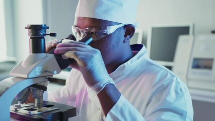 Wall Mural - professional scientist in protective gear examining biological sample through microscope, conducting