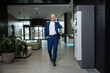 © zinkevych - Businessman in suit walking through office corridor while phoning with smartphone