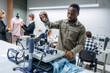 © standret - Black man is standing by the table. People are working by the sewing machines indoors